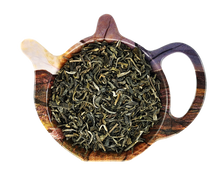 Suszona zielona herbata Mao Feng Vietnam o lekko zwiniętych listkach w drewnianym czajniczku.