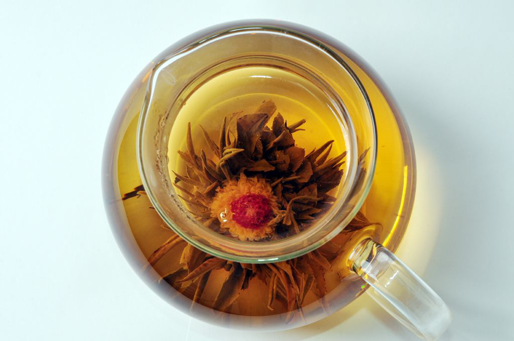 Widok z góry na dzbanek z zaparzoną herbatą rozkwitającą Flower Pearl w kształcie kwiatu.