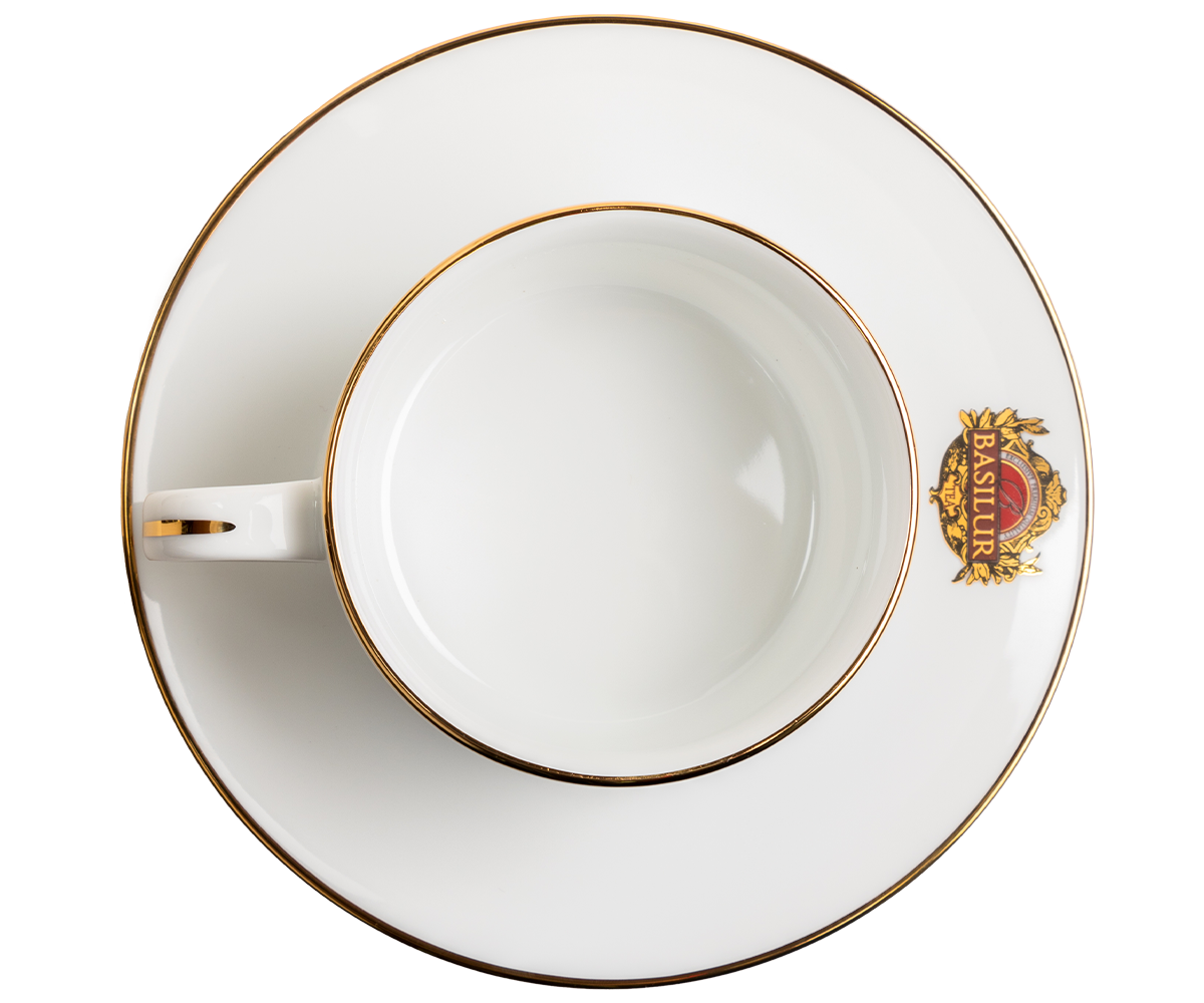 Widok z góry na filiżankę porcelanową Basilur ze spodkiem i złotym rantem.