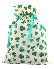 Jasny worek prezentowy w zielone koniczynki, przewiązany zieloną wstążką.