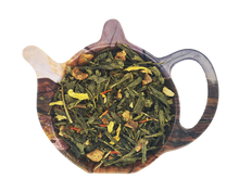 Zielona herbata Sencha Imbirowo Jablkowa z imbirem, jabłkiem i kwiatami słonecznika przedstawiona na podstawce w kształcie czajniczka