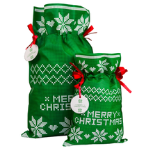 Zielony worek prezentowy z białymi wzorami gwiazdy betlejemskiej, czerwonymi wstążkami i zawieszką Merry Christmas, rozmiar 20 x 30 cm.