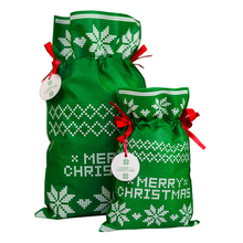 Zielony worek prezentowy z białymi wzorami gwiazdy betlejemskiej, czerwonymi wstążkami i zawieszką Merry Christmas.