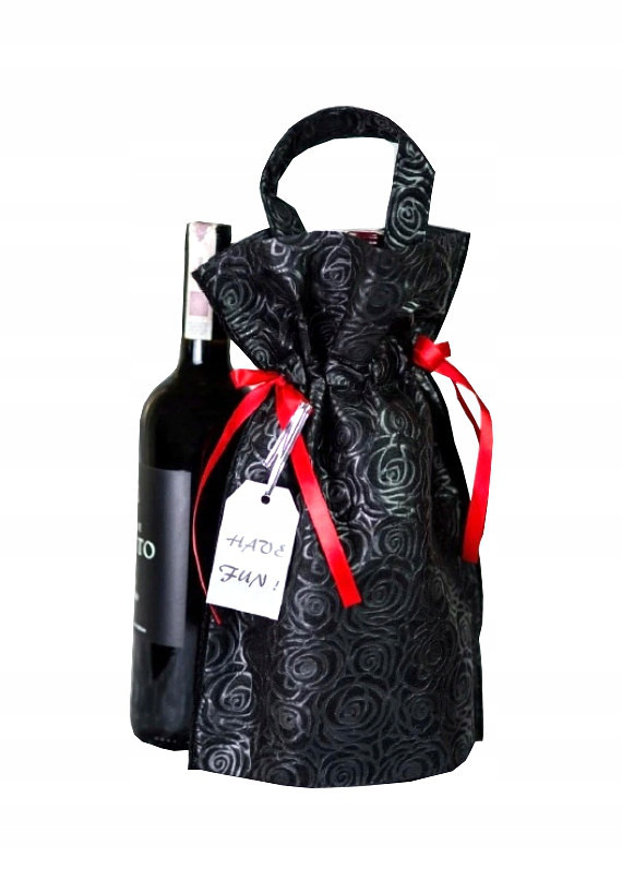 Czarny worek prezentowy 22 x 32 x 10 cm z tłoczonym wzorem róż, czerwonymi wstążkami i rączką, obok butelka wina.