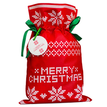 Czerwony worek prezentowy z białym świątecznym wzorem i napisem „Merry Christmas”, ozdobiony zielonymi wstążkami i zawieszką.
