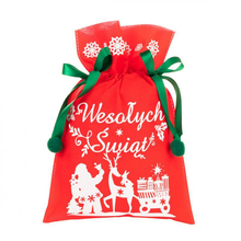 Czerwony worek prezentowy z białym nadrukiem Świętego Mikołaja, renifera i wózka z prezentami, przewiązany zielonymi wstążkami z pomponami.