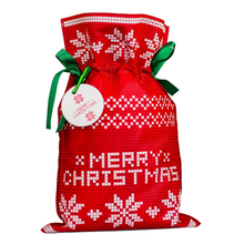 Czerwony worek prezentowy z białym wzorem w gwiazdy betlejemskie, napisem Merry Christmas i zieloną wstążką.