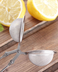 Otwarty zaparzacz do herbaty w kształcie szczypiec z widoczną siateczką