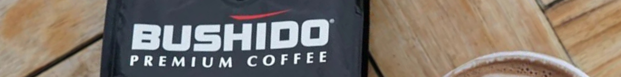 Opakowanie Bushido Premium Coffee na drewnianym tle obok filiżanki kawy.