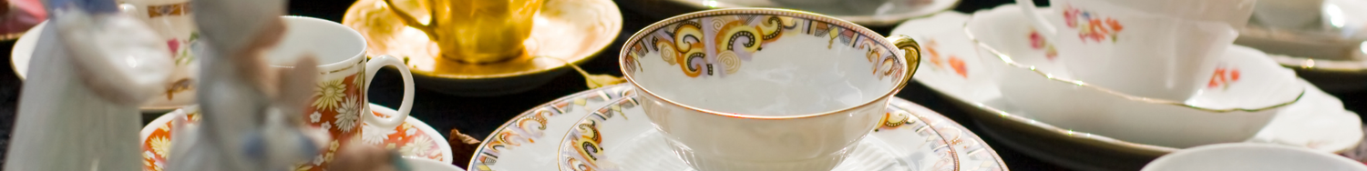 Zestaw porcelanowych filiżanek i spodków z bogatymi zdobieniami i kolorowymi wzorami kwiatowymi, ustawionych na stole.