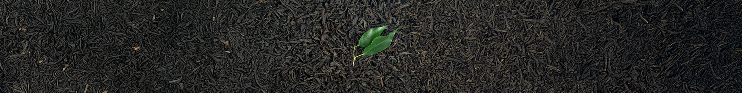 Suszone liście herbaty czarnej z zielonym listkiem na tle.