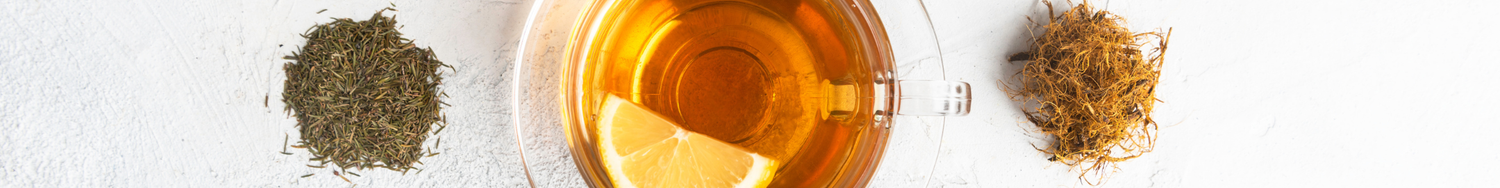 Filiżanka herbaty z cytryną na jasnym tle, obok rozsypane suszone zioła i korzenie – naturalne składniki naparu.