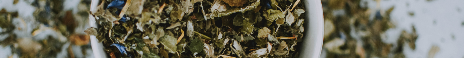 Zbliżenie na suszone liście ziół w miseczce, przedstawione jako naturalna herbata ziołowa.