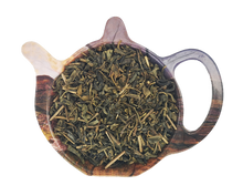 Żółta herbata chińska Huang Da Cha o drobnych liściach na podstawce w kształcie czajniczka