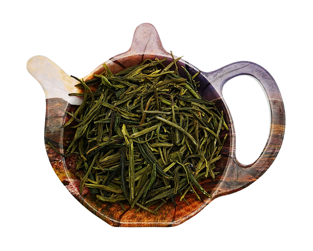 Liście chińskiej zielonej herbaty Huang Shan Mao Feng na podstawce w kształcie czajniczka