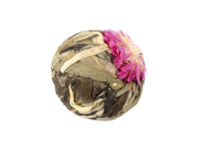 Herbata rozkwitająca Rich Flower w formie suszonej kulki z widocznym różowym kwiatem.