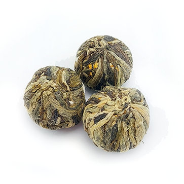 Trzy zwinięte kulki herbaty rozkwitającej Autumn Beauty widoczne przed zaparzeniem.