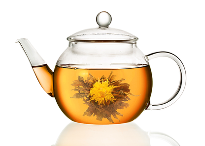 Szklany dzbanek z bursztynowym naparem oraz rozwiniętą herbatą rozkwitającą Czarna Perła.