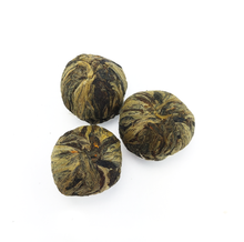 Trzy kulki herbaty rozkwitającej Lichi Flower Pearl na jasnym tle
