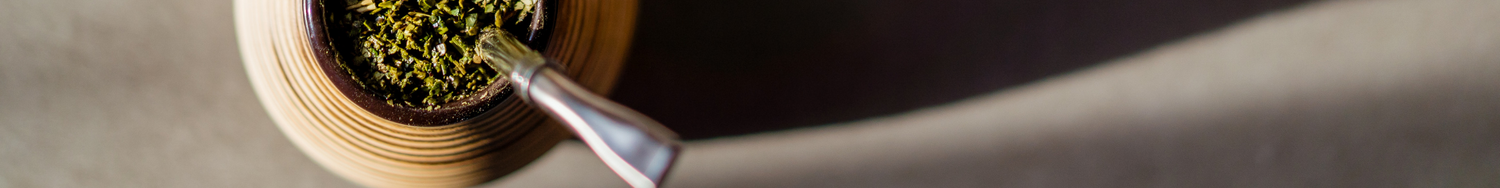 Drewniane matero z yerba mate i metalową bombillą, widok z góry na jasnym tle.