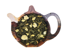 Zdjęcie zielonej herbaty Sencha Moon Light z dodatkiem mango, papai, ananasa, rumianku i słonecznika w dekoracyjnej podstawce – aromatyczna herbata zielona.