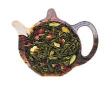 Zielona herbata Sencha Zimowe Opowiesci z pomarańcza, migdałami, goździkami i kardamonem na podstawce w kształcie czajniczka