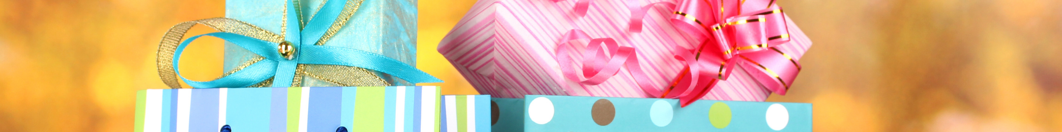 Kolorowe torby prezentowe z pudełkami owiniętymi wstążkami, w pastelowych odcieniach różu, błękitu i zieleni, na jasnym tle.